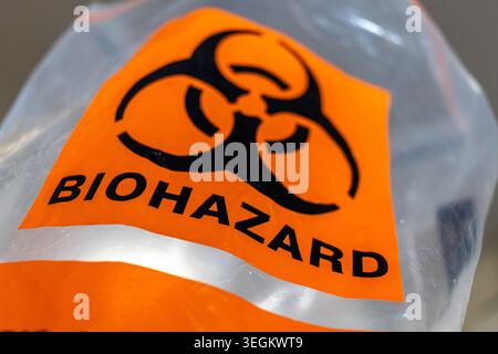 Biohazard bag, plastic bag for biohazardous waste in a hospital or laboratory, toxic waste with black biohazard symbol on orange background Stock Photo