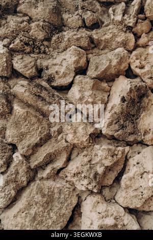 Natural limestone stones arranged in rough wall texture with beige earthy tones porous mineral surface rugged geology background organic rock pattern Stock Photo