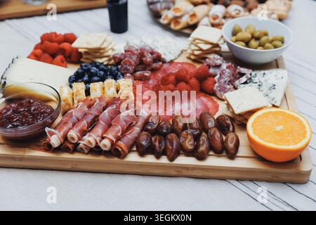 Wooden board holds assorted charcuterie and fruit Stock Photo
