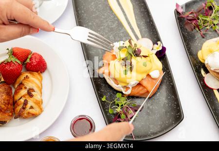 Delightful Brunch Spread Featuring Eggs Benedict and Fresh Strawberries on a Sunny Table Stock Photo