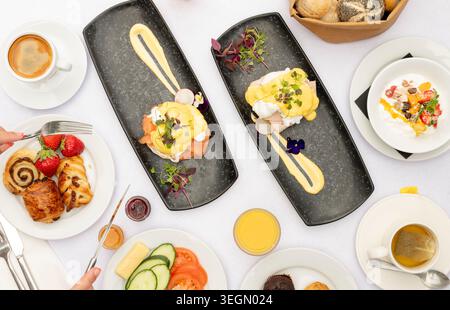 Delicious Brunch Spread With Eggs Benedict and Fresh Fruits at a Cozy Cafe Stock Photo