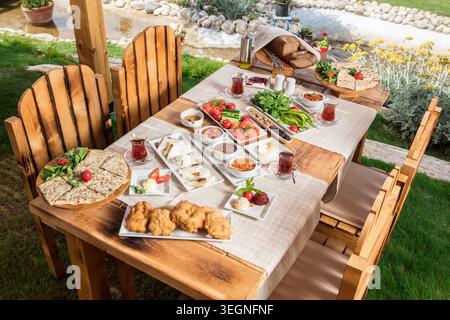 Rich Mediterranean Breakfast Served Outdoors, Abundant Traditional Turkish Breakfast with Fresh Bread, Cheese, Olives, Eggs and Seasonal Ingredients Stock Photo