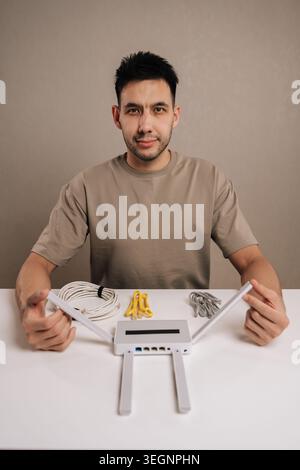Bearded handsome man working with wireless router and various cables, setting up home network connectivity, troubleshooting internet solutions for Stock Photo