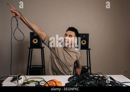 Portrait of person organizing a pile of tangled audio cables at a home studio, feeling overwhelmed by the messy wiring, working on cable management Stock Photo