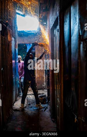 A Nairobi, Kenya worker uses a grinder to cut steel causing a shower of sparks. Stock Photo