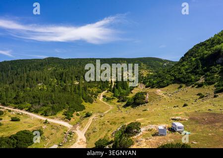 Winding Dirt Road Through Alpine Mountain Valley With Lone Caravan, Prokosko Lake Bosnia and Herzegovina Stock Photo