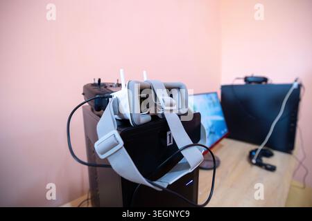 An assortment of instructional and training equipment for FPV drone pilots is arranged on a wooden desk inside a classroom, including virtual reality Stock Photo