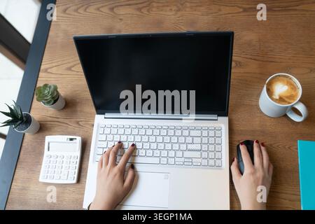Overhead shot of female hands typing on a laptop keyboard in a modern remote work setup with wireless mouse and office accessories. Clean and minimal Stock Photo