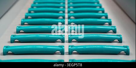 Rows of Turquoise Plastic Handles on Factory Conveyor Belt Stock Photo