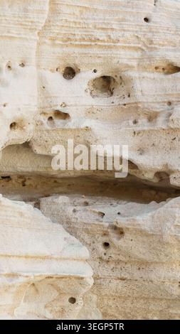 A detailed closeup of a rough, aged stone wall texture showing a natural brown rock surface pattern with a vintage, grunge background design Stock Photo