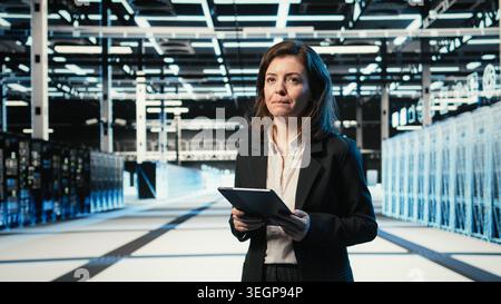 Smiling data center DevOps technician optimizing server load balancing using tablet app. Happy server hub employee worker adjusting system parameters on device to improve efficiency Stock Photo