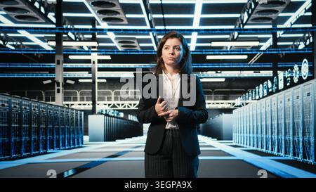 Inspecting hardware, blue wireframe mesh rackmounts and manager in data center. Looking at AR data streams, digital twin simulation and system administrator walking through server hub rows Stock Photo