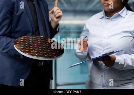 Planning semiconductor substrate upgrades, business meeting and researchers in smart factory. Evaluating advanced microchips prototype, silicon wafer close up and professionals Stock Photo