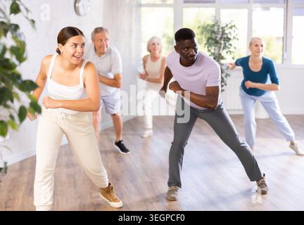 Female instructor teaches mature students of dance class basic movements of hip hop dance Stock Photo