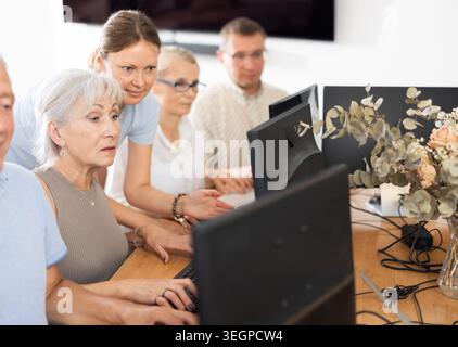 Young female mentor explaining something to elderly woman at computer lesson Stock Photo