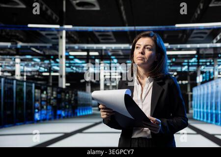 Data center technician auditing documentation to ensure database security, doing systems management. Server hub expert checks technical files for accuracy, planning disaster recovery protocols Stock Photo