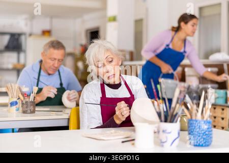 female potter paints finished vase in white Stock Photo