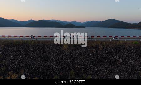 Happy friends raising hands on mae kuang dam road overlooking reservoir and mountains Stock Photo