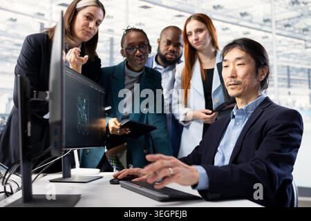 Microchip industrial plant office workers using AI model to conduct RD study on SoC architecture design. Multiethnic scientists at PC desk developing semiconductors tech using artificial intelligence Stock Photo