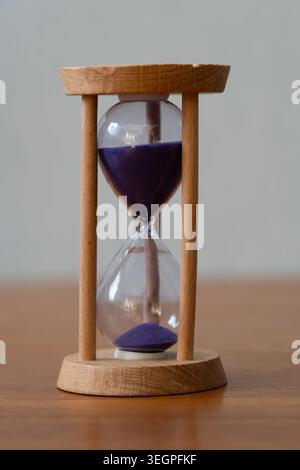 Wooden Hourglass with Purple Sand on Table for Time Management,Traditional Wooden Hourglass Symbolizing Deadlines and History, vertical image Stock Photo
