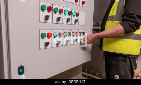 Electrical service engineer testing control panel faults in an HVAC control cabinet . Electrician fault finding on air conditioning and ventilation co Stock Photo