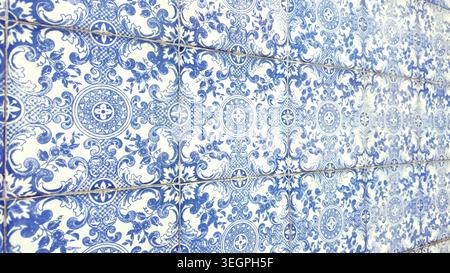 A sweeping, angled view of a wall adorned with traditional Portuguese azulejo tiles, featuring detailed blue floral and scrollwork designs on a white Stock Photo