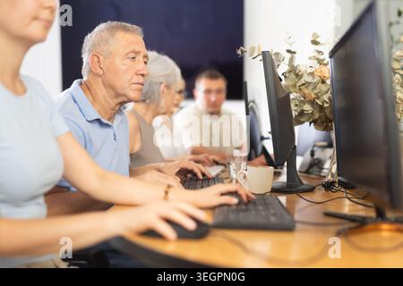 Side view of mature people while studying in computer lab in nursing home Stock Photo