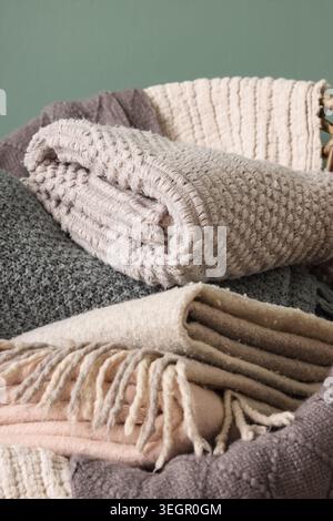 Wicker chair with different cozy blankets on turquoise background, closeup Stock Photo