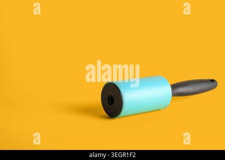 Lint roller on yellow background Stock Photo