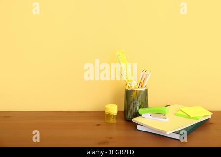 Holder with different stationery and notebooks on wooden desk Stock Photo