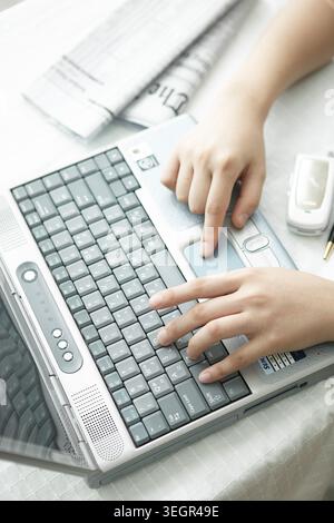 A person types on a laptop keyboard in a bright, airy office. Stock Photo