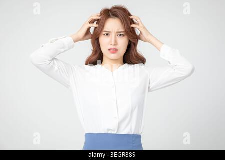 A young woman with a worried expression, holding her temples and looking off to the side. Stock Photo