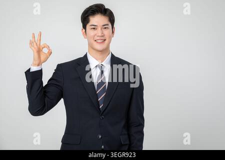 A young Asian business executive gives a satisfied "okay" gesture with his hand. Stock Photo