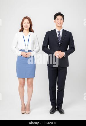A young Asian woman and a young Asian man in business attire stand side by side, smiling. Stock Photo