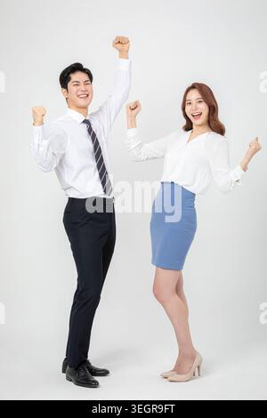 A young man and woman in business attire celebrate with raised fists. Stock Photo