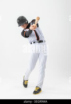 A baseball player swings his bat with a focus on hitting the ball. Stock Photo