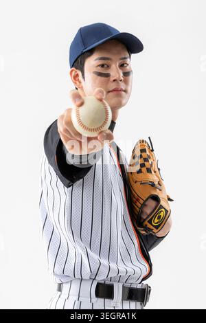 A baseball player is throwing a baseball with a baseball glove in hand. Stock Photo
