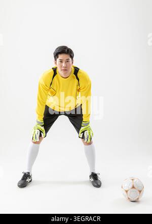 A male soccer goalkeeper in a crouched position, ready to make a save. Stock Photo