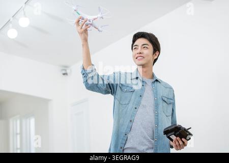 Smiling male Kidult playing with a drone Stock Photo