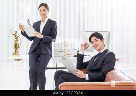 A businessman and a lawyer are working together in a modern office, reviewing documents and smiling. Stock Photo
