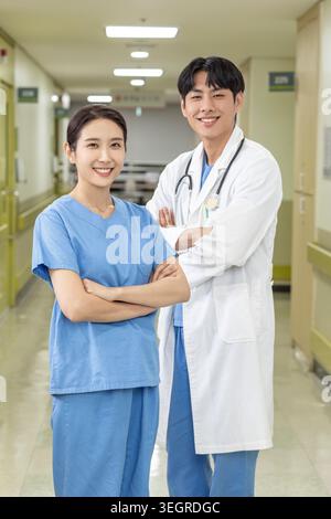 Two doctors in a hospital corridor, smiling and standing together. Stock Photo