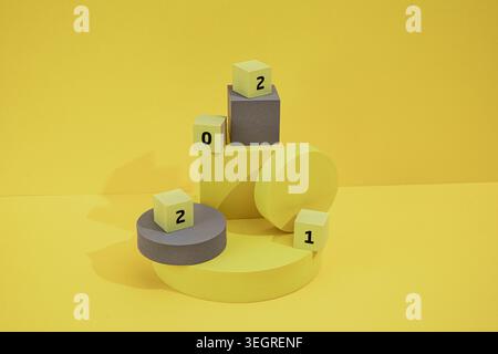 A stack of yellow and grey cubes and blocks of various shapes and sizes, arranged on a yellow surface, with some blocks bearing the number 2. Stock Photo