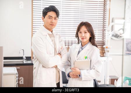 Two smiling medical professionals in a modern dental clinic, standing together and looking at the camera. Stock Photo