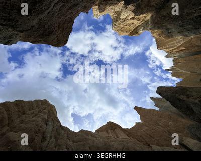Looking Up Through Jagged Clay Cliffs Canyon Opening to Blue Sky and Clouds in New Zealand Stock Photo