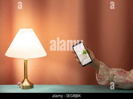 A woman's hand holds a smartphone, capturing a still life of a vase with tulips in a studio setting. Stock Photo