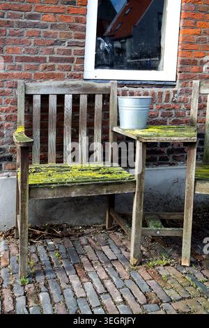 Outdoor view of a wooden old chair and table covered with moss Stock Photo