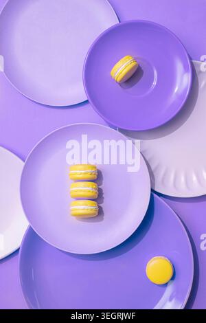 A selection of colorful macarons are arranged on a series of plates in a vibrant, modern setting. Stock Photo