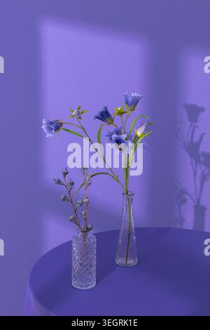A bouquet of blue flowers is arranged in three glass vases on a round, dark table. Stock Photo