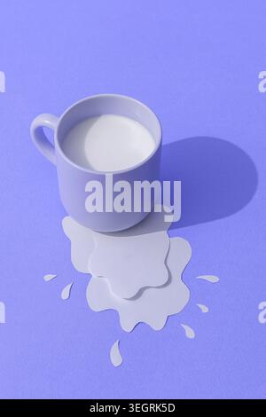 A white coffee cup spills its contents on a purple background. Stock Photo