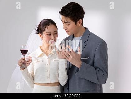 A young couple, newly married, share a toast with wine and exchange rings in a romantic, candle-lit setting. Stock Photo
